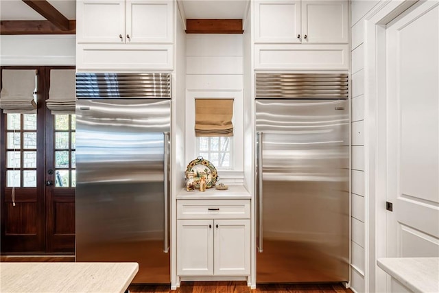 kitchen featuring white cabinetry, built in fridge, and beamed ceiling