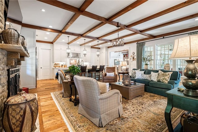 living room featuring beamed ceiling, a fireplace, coffered ceiling, and light wood-type flooring