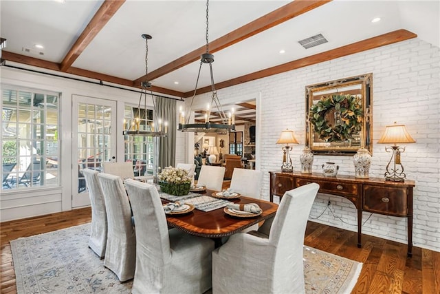 dining space featuring dark wood-type flooring, a notable chandelier, brick wall, and beamed ceiling