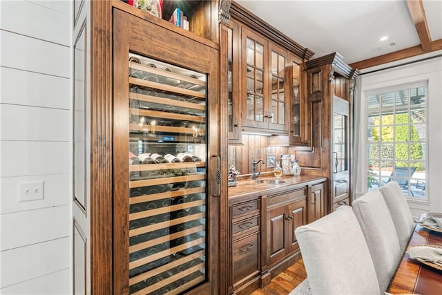 bar with sink, wooden walls, beverage cooler, and dark hardwood / wood-style flooring