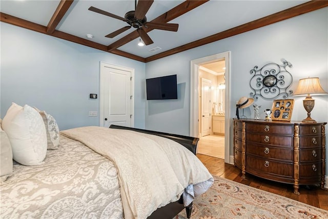 bedroom featuring beamed ceiling, ensuite bath, dark hardwood / wood-style flooring, and ceiling fan