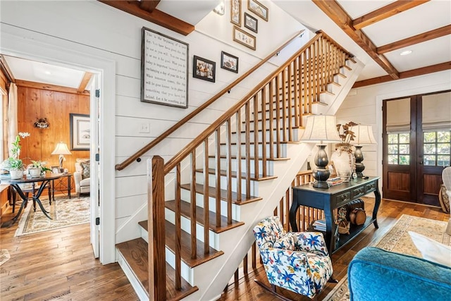 staircase with hardwood / wood-style flooring, wood walls, beam ceiling, and french doors