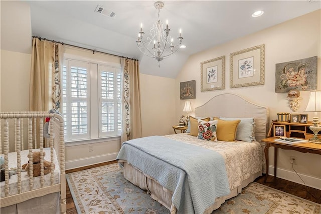 bedroom with lofted ceiling, hardwood / wood-style floors, and an inviting chandelier