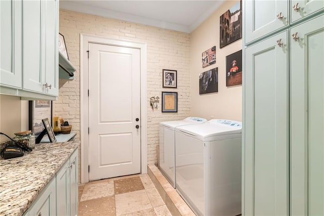 laundry area with crown molding, washer and clothes dryer, cabinets, and brick wall