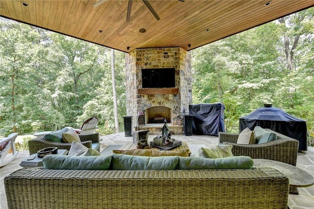 view of patio featuring ceiling fan, an outdoor living space with a fireplace, and area for grilling