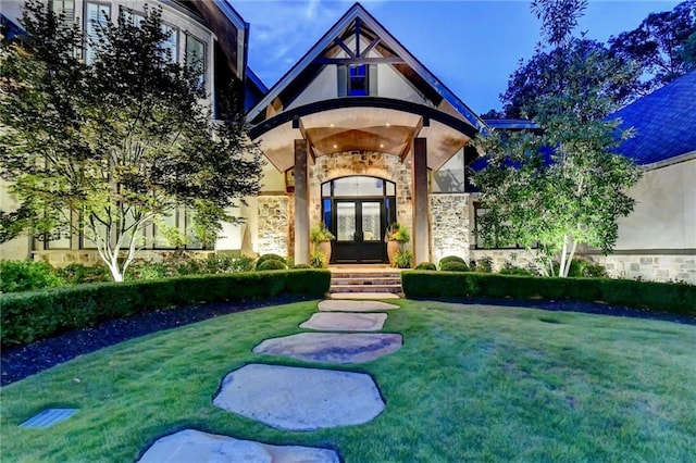 view of exterior entry featuring french doors and a lawn