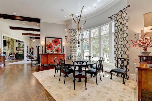 dining space featuring light wood-type flooring, beam ceiling, ornamental molding, and an inviting chandelier