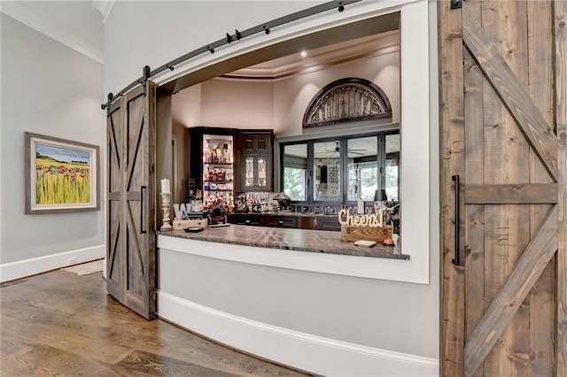 bar with ornamental molding, hardwood / wood-style flooring, and a barn door