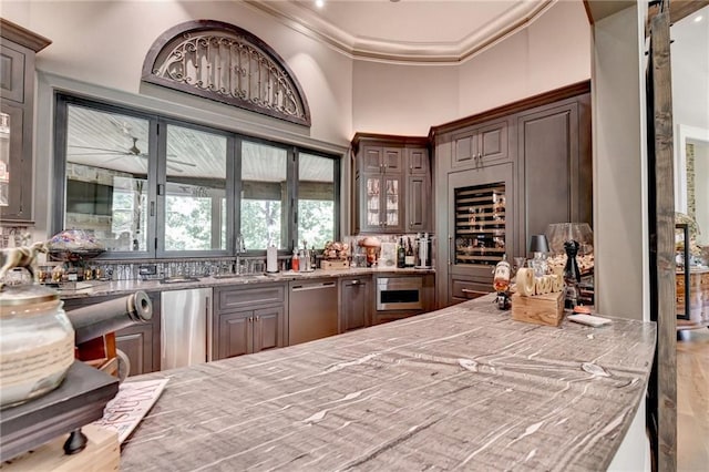 bar featuring sink, dark brown cabinetry, ornamental molding, and stainless steel dishwasher