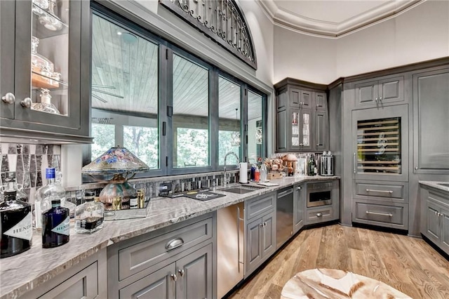 kitchen featuring wine cooler, sink, backsplash, ornamental molding, and light stone counters