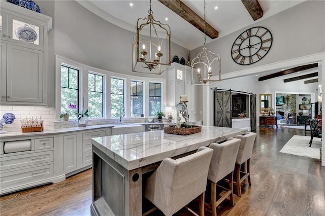 kitchen with a center island, beamed ceiling, white cabinetry, and a barn door