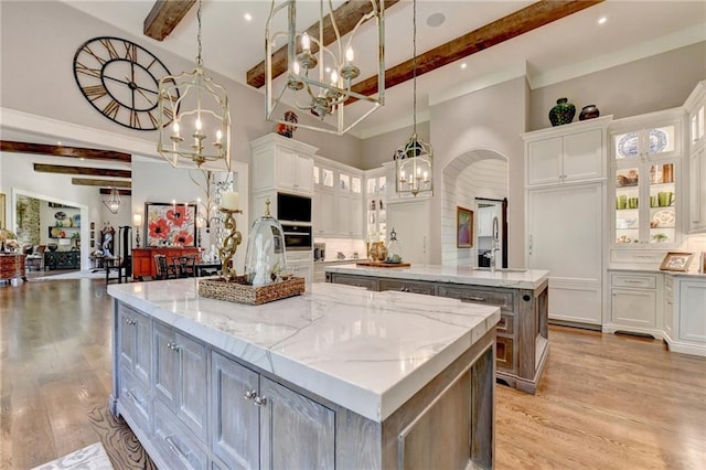 kitchen with a spacious island, pendant lighting, white cabinets, and beam ceiling