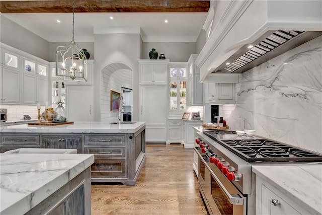 kitchen featuring premium range hood, white cabinets, and range with two ovens