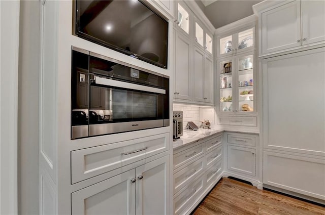 kitchen featuring light stone countertops, white cabinets, light hardwood / wood-style flooring, and stainless steel oven