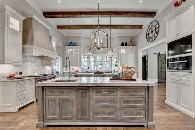 kitchen with a barn door, white cabinets, and an island with sink