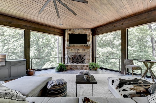 sunroom featuring a fireplace, wooden ceiling, a healthy amount of sunlight, and ceiling fan