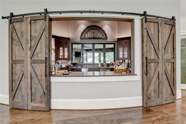 bar with hardwood / wood-style flooring and a barn door