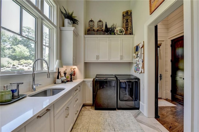 clothes washing area featuring cabinets, light tile patterned floors, separate washer and dryer, and sink