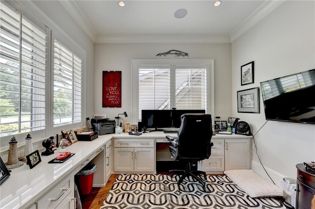 office area featuring plenty of natural light, built in desk, and ornamental molding