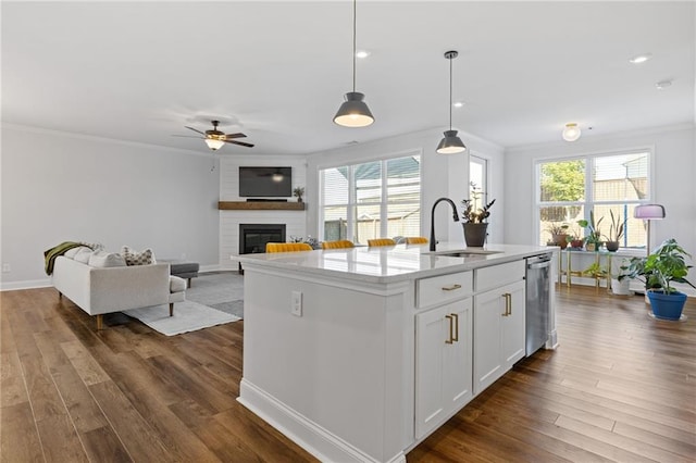 kitchen featuring pendant lighting, dishwasher, a kitchen island with sink, sink, and white cabinetry