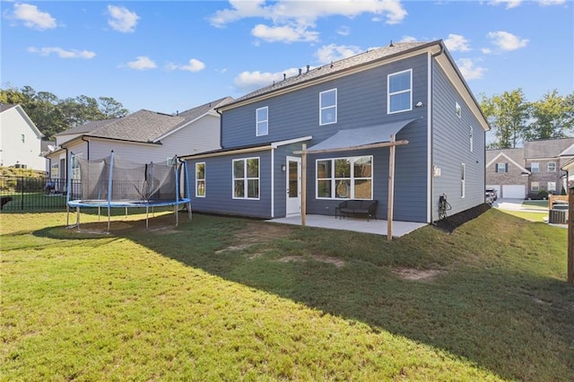 back of house with a yard, a trampoline, and a patio area