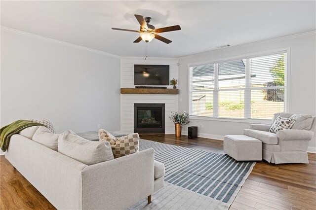 living room featuring ceiling fan, a fireplace, hardwood / wood-style floors, and ornamental molding