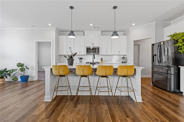 kitchen with a center island with sink, decorative light fixtures, white cabinetry, and stainless steel appliances