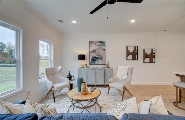 living room with ceiling fan, a healthy amount of sunlight, ornamental molding, and light hardwood / wood-style flooring