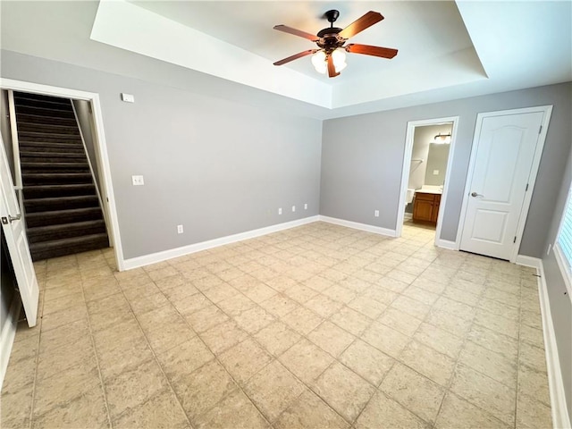 8967 Midlothian Ct, Winston, GA 30187 - unfurnished bedroom featuring a tray ceiling, baseboards, light floors, ensuite bathroom, and a ceiling fan