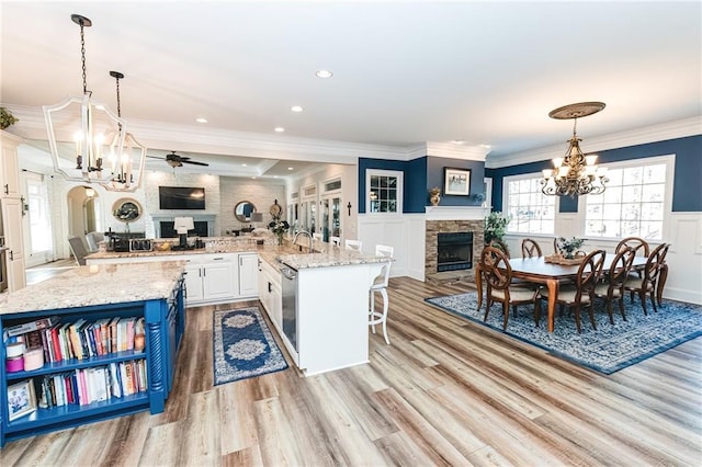 kitchen featuring a spacious island, a wainscoted wall, ornamental molding, a fireplace, and white cabinets