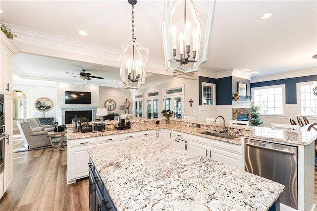 kitchen with a large fireplace, open floor plan, a large island, stainless steel appliances, and a sink