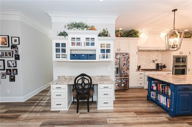 office area featuring wood finished floors, baseboards, ornamental molding, built in desk, and a chandelier