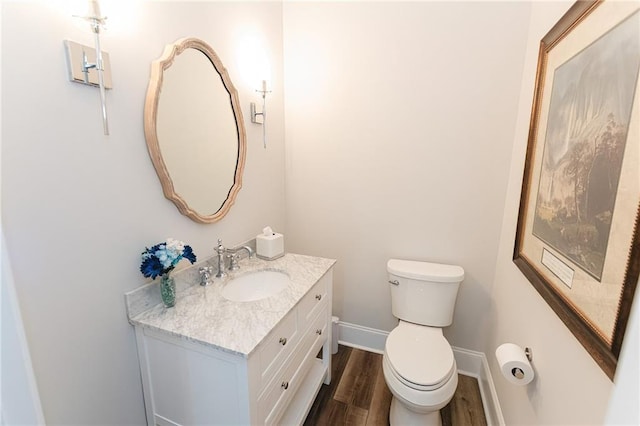 bathroom with toilet, vanity, baseboards, and wood finished floors