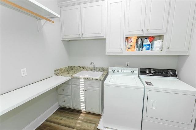 washroom featuring a sink, baseboards, dark wood finished floors, cabinet space, and separate washer and dryer