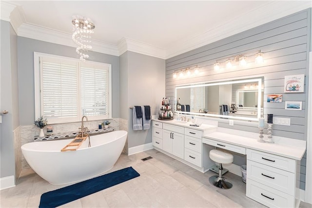 full bath featuring a chandelier, a soaking tub, vanity, and ornamental molding