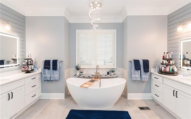 full bath featuring visible vents, a soaking tub, two vanities, crown molding, and a chandelier