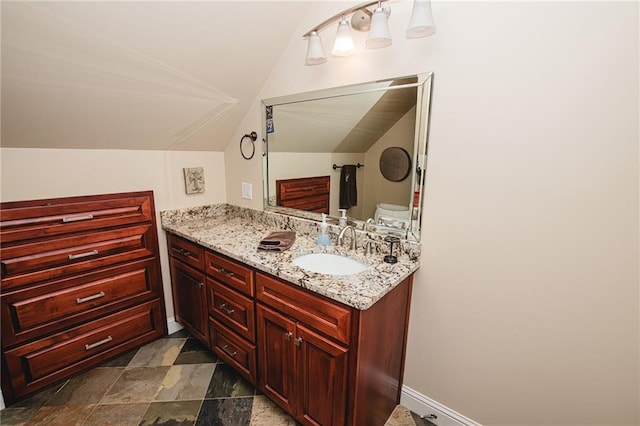 bathroom with stone finish flooring, baseboards, vanity, and vaulted ceiling