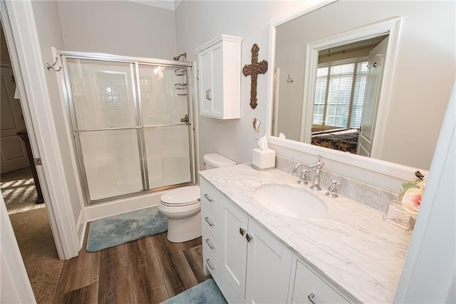 bathroom featuring wood finished floors, toilet, a stall shower, and vanity