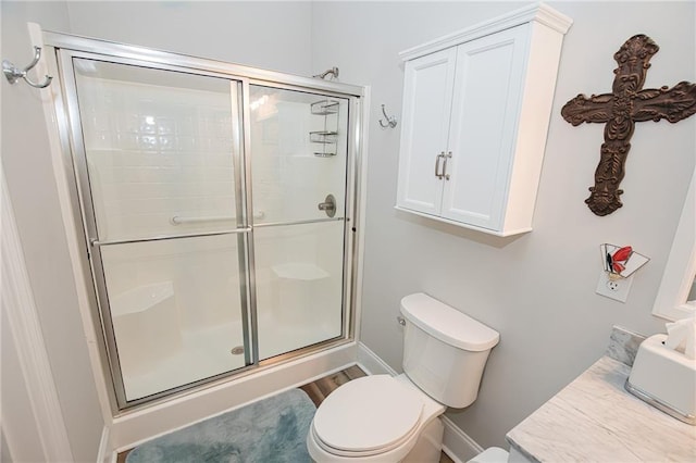 bathroom featuring a shower stall, toilet, and baseboards