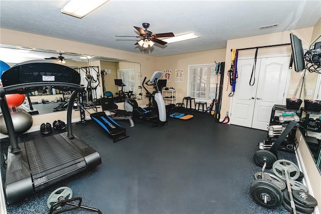 workout area featuring visible vents, a textured ceiling, and a ceiling fan