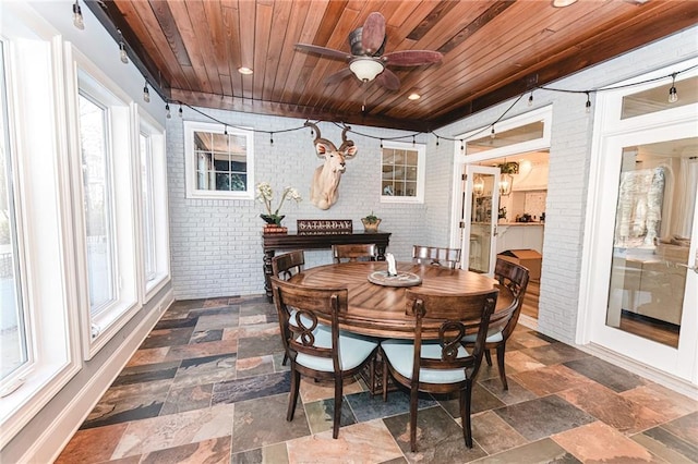 dining space featuring a ceiling fan, stone tile flooring, recessed lighting, brick wall, and wood ceiling