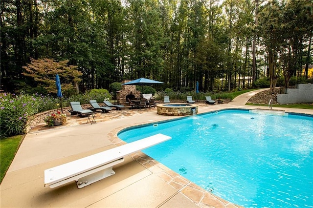 view of swimming pool featuring a patio area, a pool with connected hot tub, and a diving board