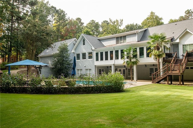 back of property featuring a wooden deck, a lawn, stairs, and a patio area