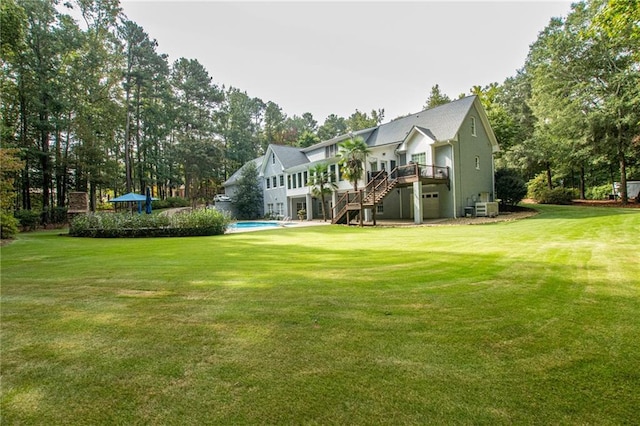 rear view of house with a lawn, a wooden deck, stairs, and a garage