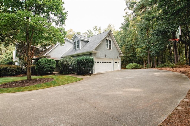 view of side of property featuring driveway, a garage, and roof with shingles