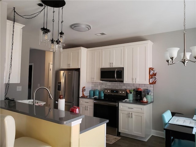 kitchen featuring pendant lighting, white cabinetry, appliances with stainless steel finishes, and a kitchen bar