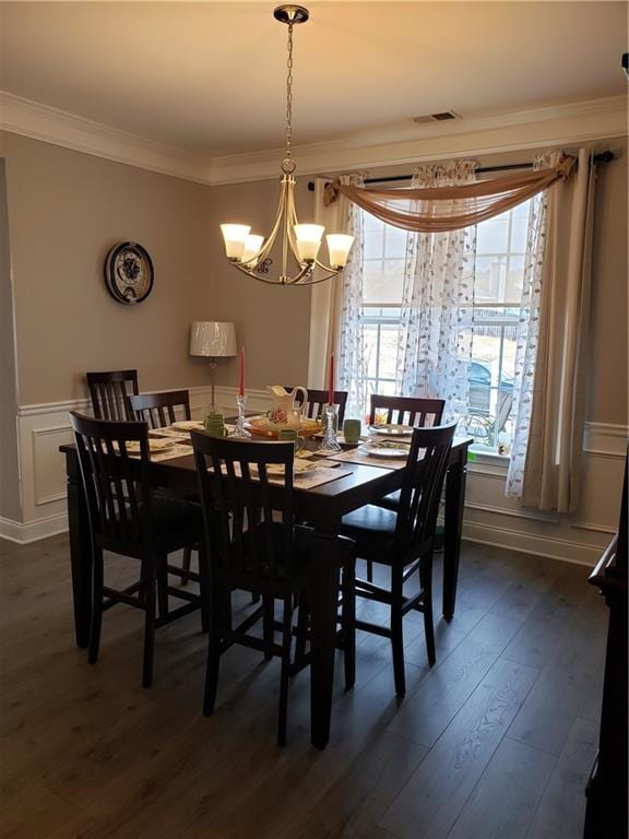 dining space featuring dark hardwood / wood-style flooring, ornamental molding, and an inviting chandelier