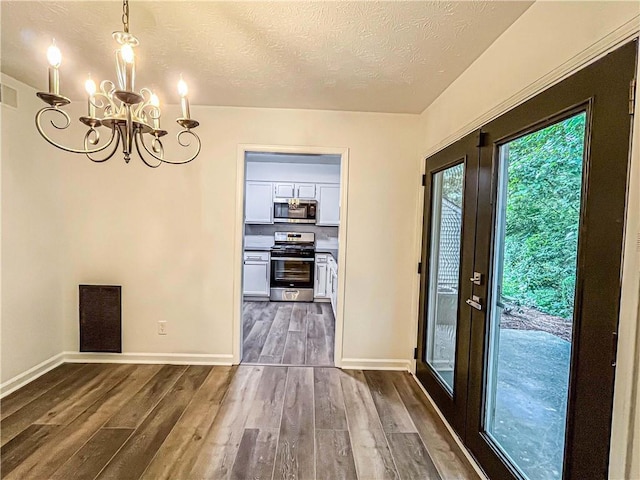 3150 Stratford Green Pl, Avondale Estates, GA 30002 - unfurnished dining area with a chandelier, dark wood-type flooring, and a textured ceiling