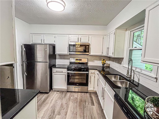 3150 Stratford Green Pl, Avondale Estates, GA 30002 - kitchen with stainless steel appliances, light wood finished floors, a textured ceiling, white cabinetry, and washer / dryer