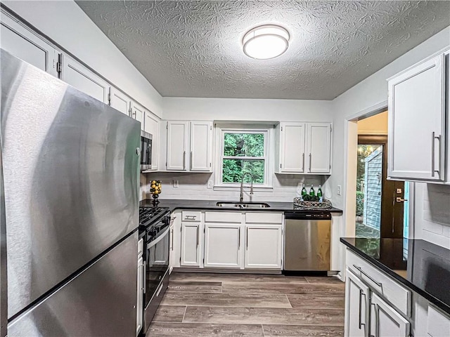 3150 Stratford Green Pl, Avondale Estates, GA 30002 - kitchen featuring stainless steel appliances, dark countertops, dark wood-style floors, a textured ceiling, and white cabinets